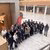 Group of about 30 professionals in business attire standing in a marble atrium, viewed from above.